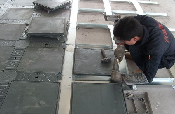 Kỹ thuật viên đang cắt lỗ tấm sàn nâng để lắp hộp điện